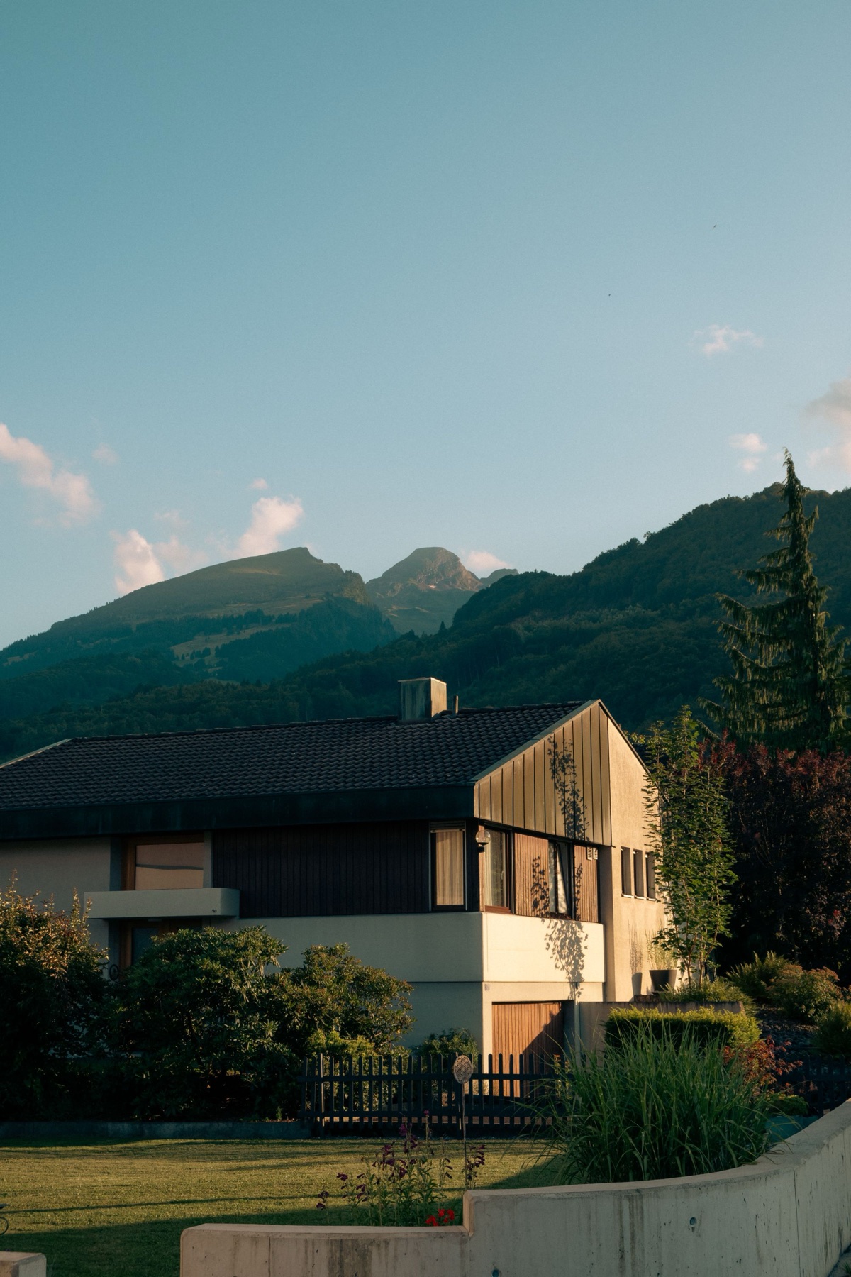 Maison contemporaine en bois et pierre devant une chaîne de sommets